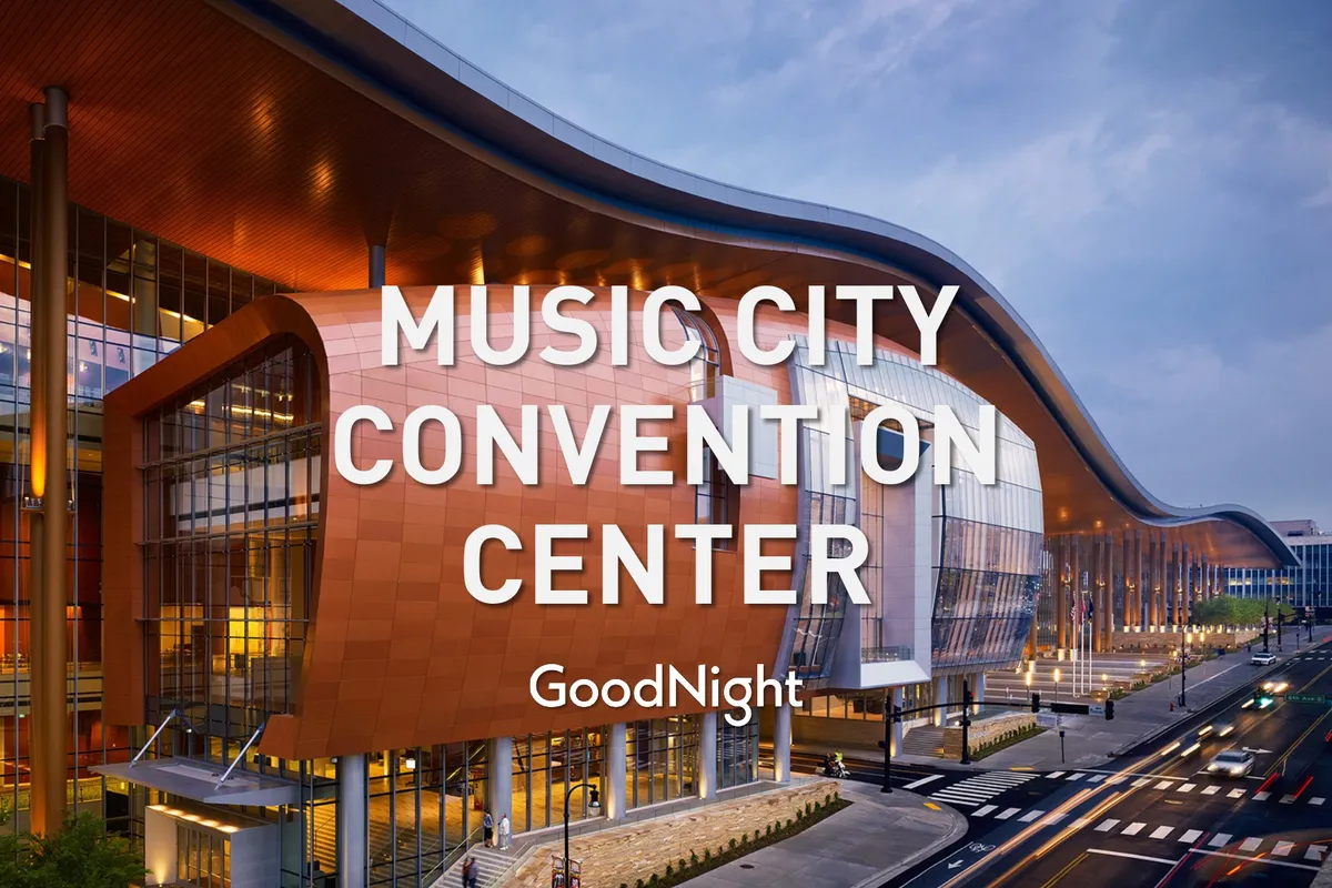 Showcasing the distinctive wavy roofline and illuminated facade of Music City Center, this shot captures the building at dusk, bustling with energy and activity. The modern architectural elements highlight Nashville's vibrant business district environment.
