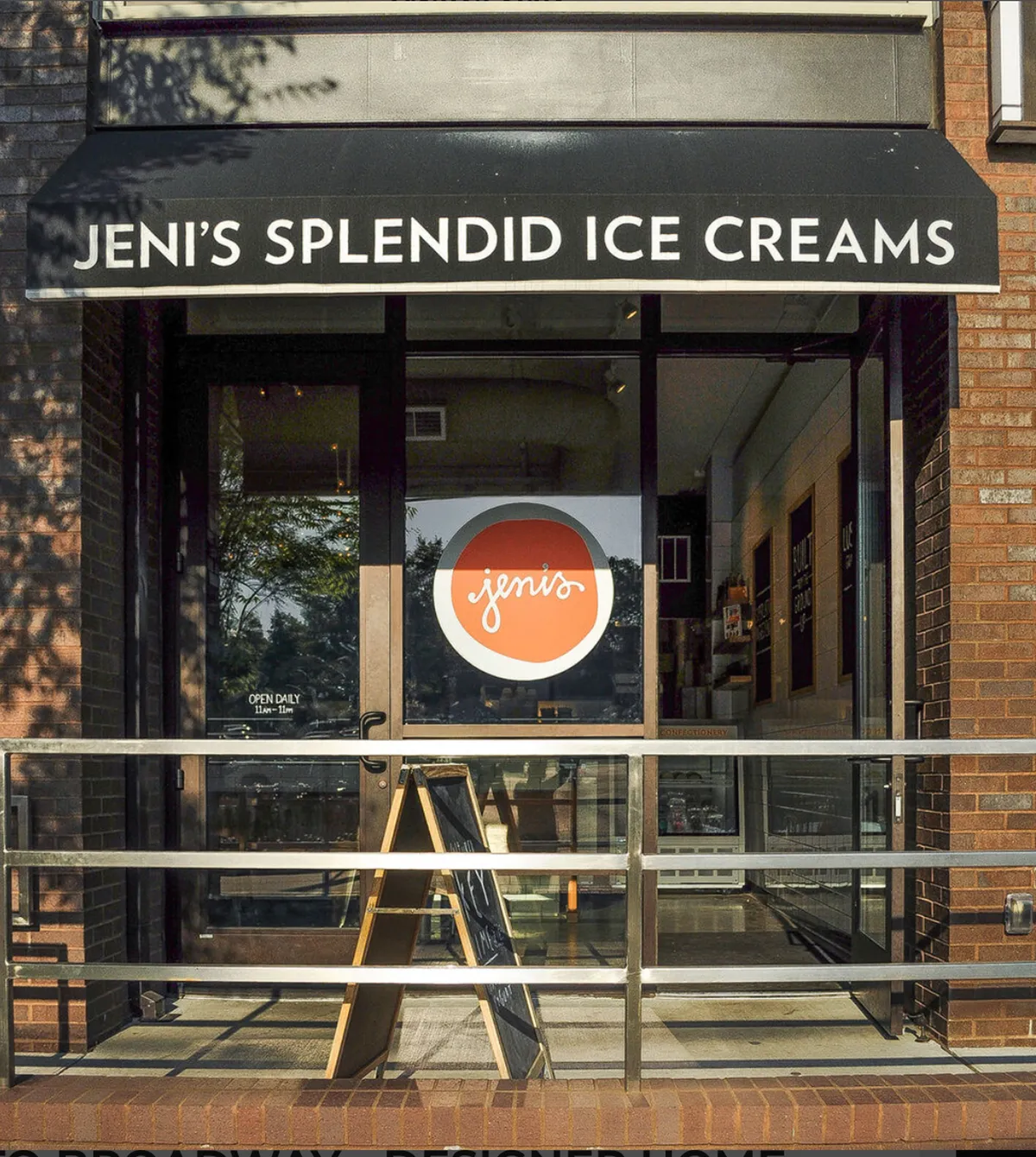 An exterior shot of Jeni’s Splendid Ice Creams storefront, with a glass door, menu board, and the joyful vibe of people enjoying ice cream on the patio. The overall mood is cheerful and welcoming—perfect for families and kids.