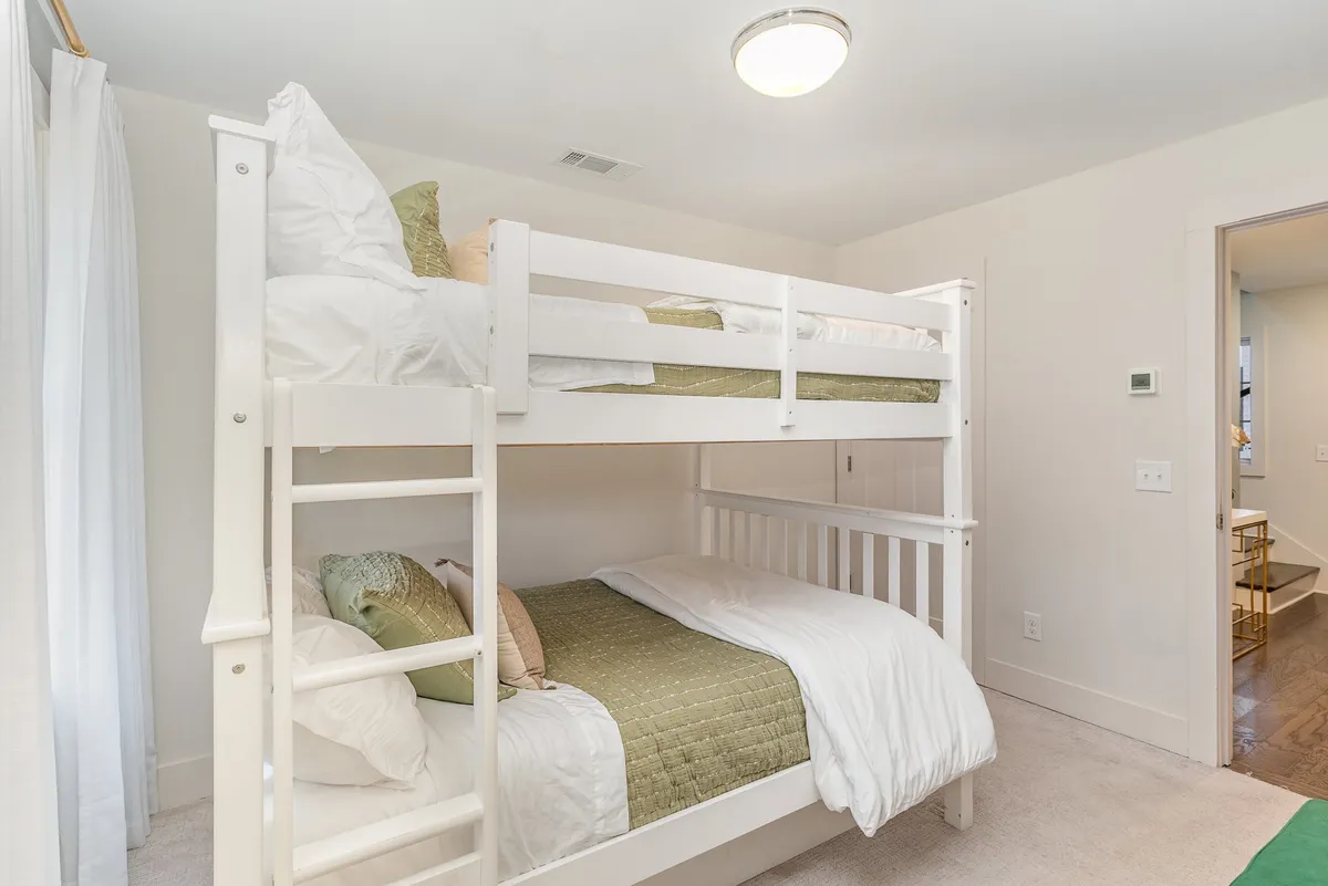 This image highlights a cheerful, kid-friendly bedroom with playful bunk beds, decorative pillows, and soft bedding. The arrangement and ambiance suggest flexible sleeping options, ideal for accommodating families or groups with children.